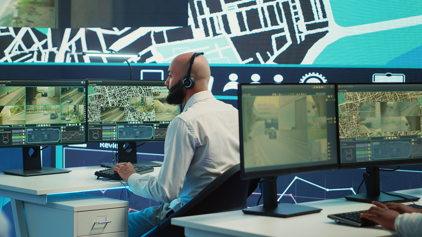 Person with headset monitoring security monitor screens