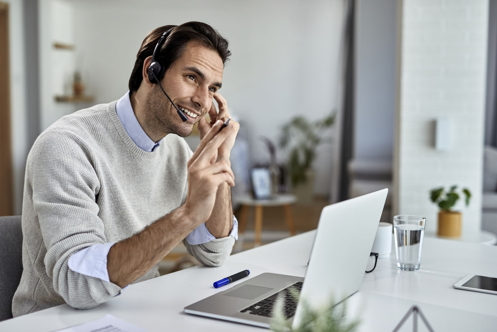 person smiling with headset on in front of laptop