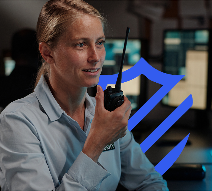 Person with a hand held walkie-talkie with One Call Alarm shield behind them